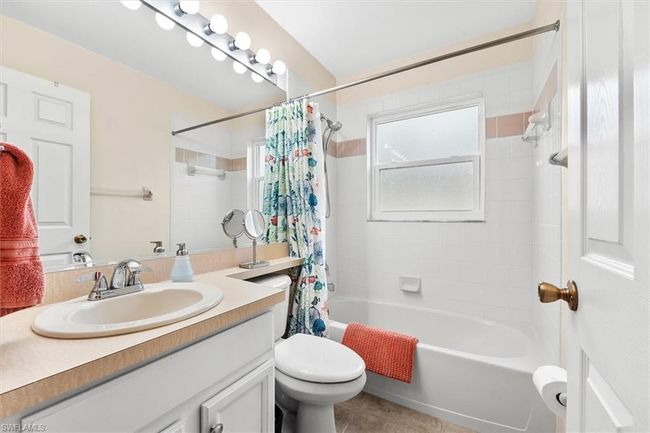 Bathroom with toilet, shower / bathtub combination with curtain, vanity, and tile patterned flooring | Image 8