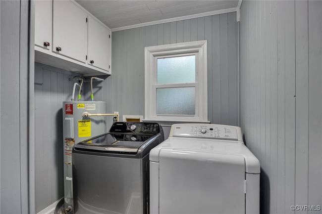 Laundry area featuring separate washer and dryer, electric water heater, cabinet space, and wood panel​​‌​​​​‌​​‌‌​‌‌​​​‌‌​​‌‌​‌​​​​​‌ walls | Image 20