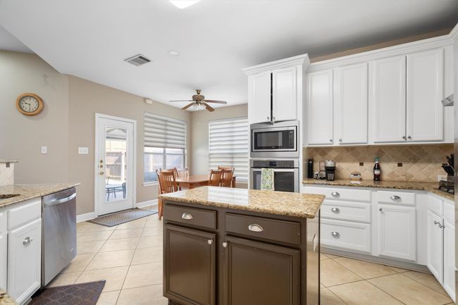 Kitchen with stainless steel appliances, backsplash, and light tile patterned floors | Image 18