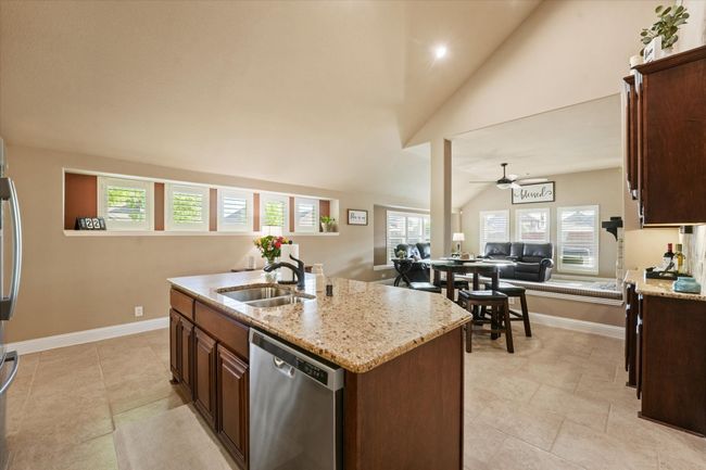 Kitchen featuring a sink, open floor plan, dishwasher, ceiling fan, and lofted ceiling | Image 11