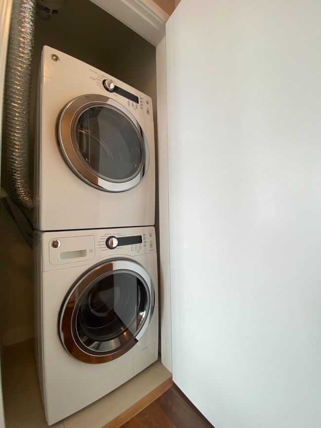 Laundry room with stacked washer / drying machine and wood finished floors | Image 11