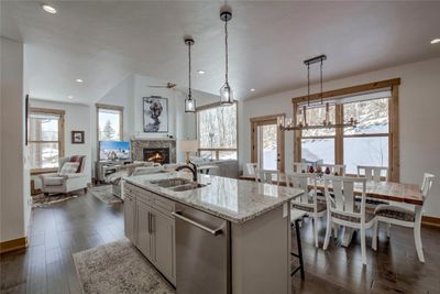 Kitchen with dishwasher, dark wood-type flooring, a center island with sink, sink, and decorative light fixtures | Image 3