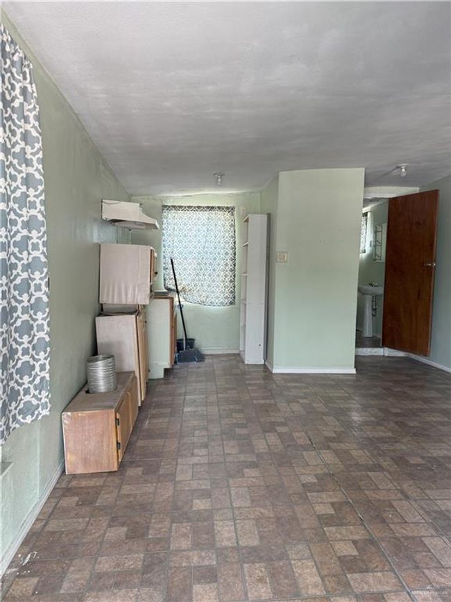 Unfurnished living room featuring baseboards and brick floor | Image 10