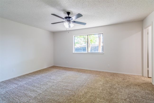 Empty room with carpet floors, a ceiling fan, a textured ceiling, and baseboards | Image 18