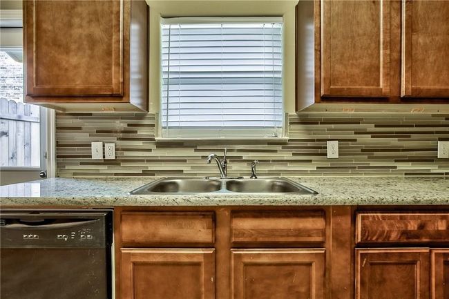 Kitchen featuring dishwashing machine, tasteful backsplash, and light stone counters | Image 5