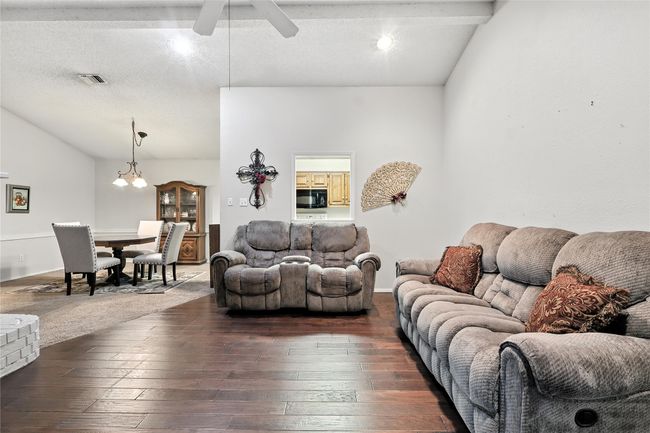 Living area with dark wood finished floors, ceiling fan, vaulted ceiling, and a textured ceiling | Image 13