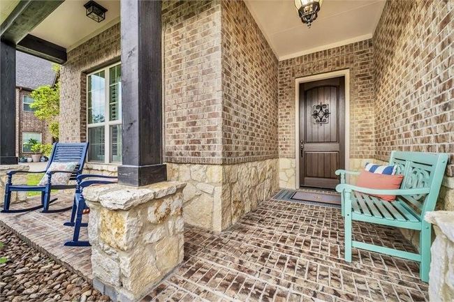 Charming covered front porch features an inviting seating area, classic brick and stone accents, and a welcoming entryway perfect for relaxing or greeting guests. | Image 6