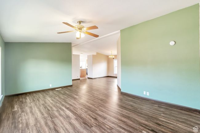 Spare room with wood finished floors, ceiling fan, baseboards, a chandelier, and lofted ceiling | Image 8