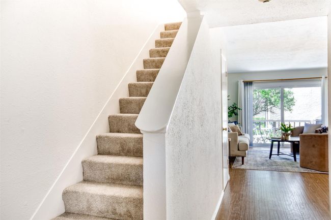 Staircase with wood finished floors and a textured wall | Image 4