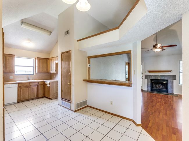 Kitchen featuring dishwasher, lofted ceiling, ceiling fan, light countertops, and a tile fireplace | Image 12