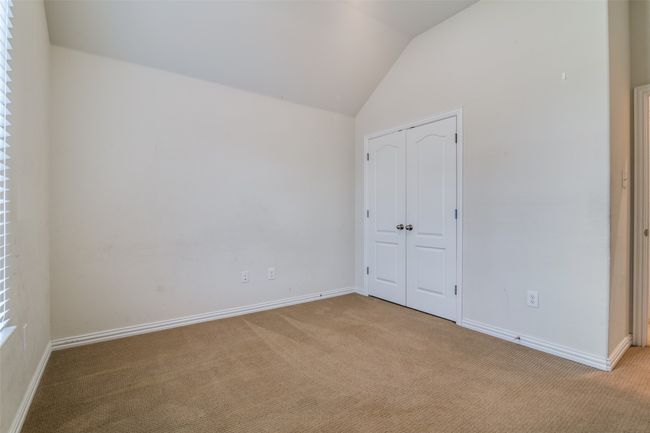Another view of the 2nd guest bedroom with light carpet, lofted ceiling, and a closet | Image 21