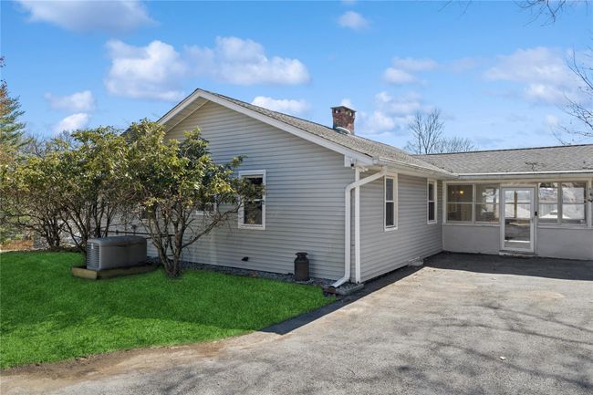 Rear view of house with a patio, a sunroom, a yard, a shingled roof, and a chimney | Image 6