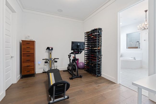 Workout area featuring light wood finished floors, ornamental molding, and a chandelier | Image 26