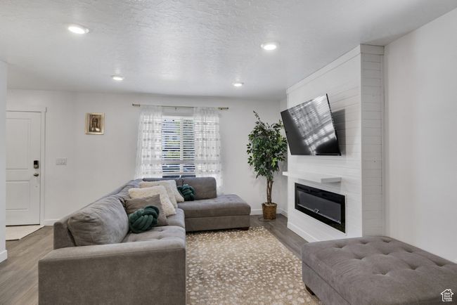 Living room featuring wood finished floors, a large fireplace, recessed lighting, and baseboards | Image 6