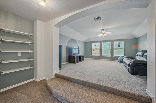 Carpeted living area with arched walkways, ceiling fan, and baseboards | Image 26