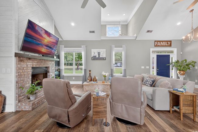 Living room with a ceiling fan, plenty of natural light, a brick fireplace, wood finished floors, and lofted ceiling | Image 10