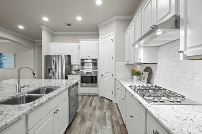 Luxurious granite countertops and premium stainless-steel appliances, including a gas cooktop, elevate the kitchen’s design. | Image 12