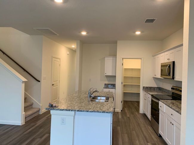 Kitchen with stainless steel appliances, dark wood-style flooring, white cabinets, and recessed lighting | Image 11