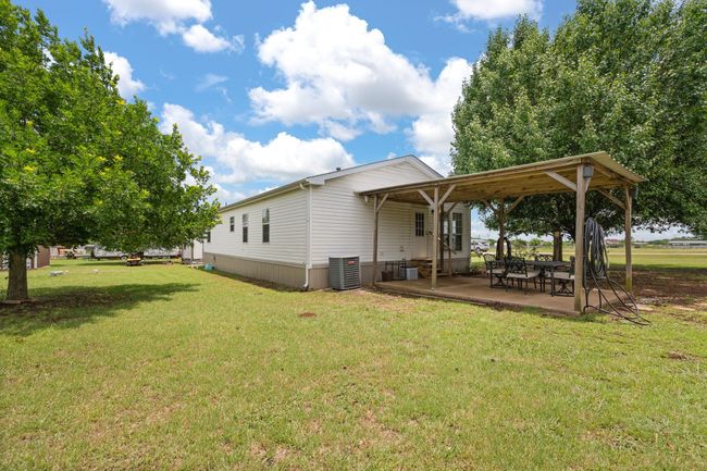 Rear view of property featuring central AC unit, a yard, and a patio area | Image 28
