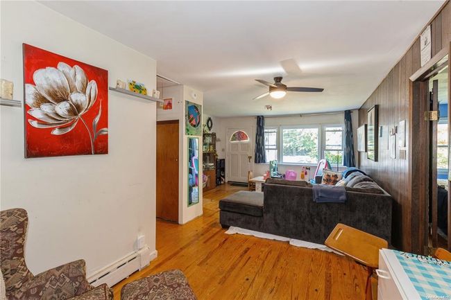 Living area featuring light wood-type flooring, a ceiling fan, and baseboard heating | Image 13