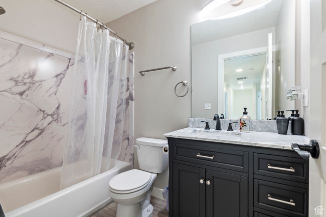 Full bathroom with shower / bath combination with curtain, wood finished floors, visible vents, toilet, and vanity | Image 35