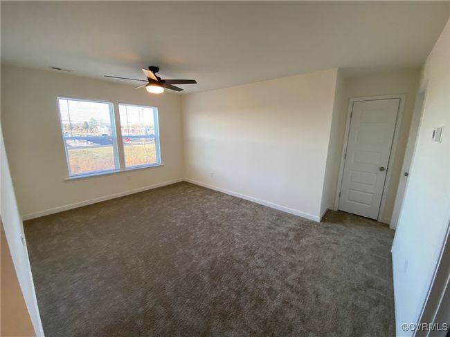 Empty room featuring dark carpet, a ceiling fan, and baseboards | Image 25