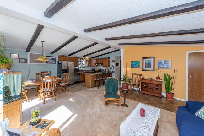 Living room featuring light carpet, vaulted ceiling with beams, a textured ceiling, and baseboards | Image 4