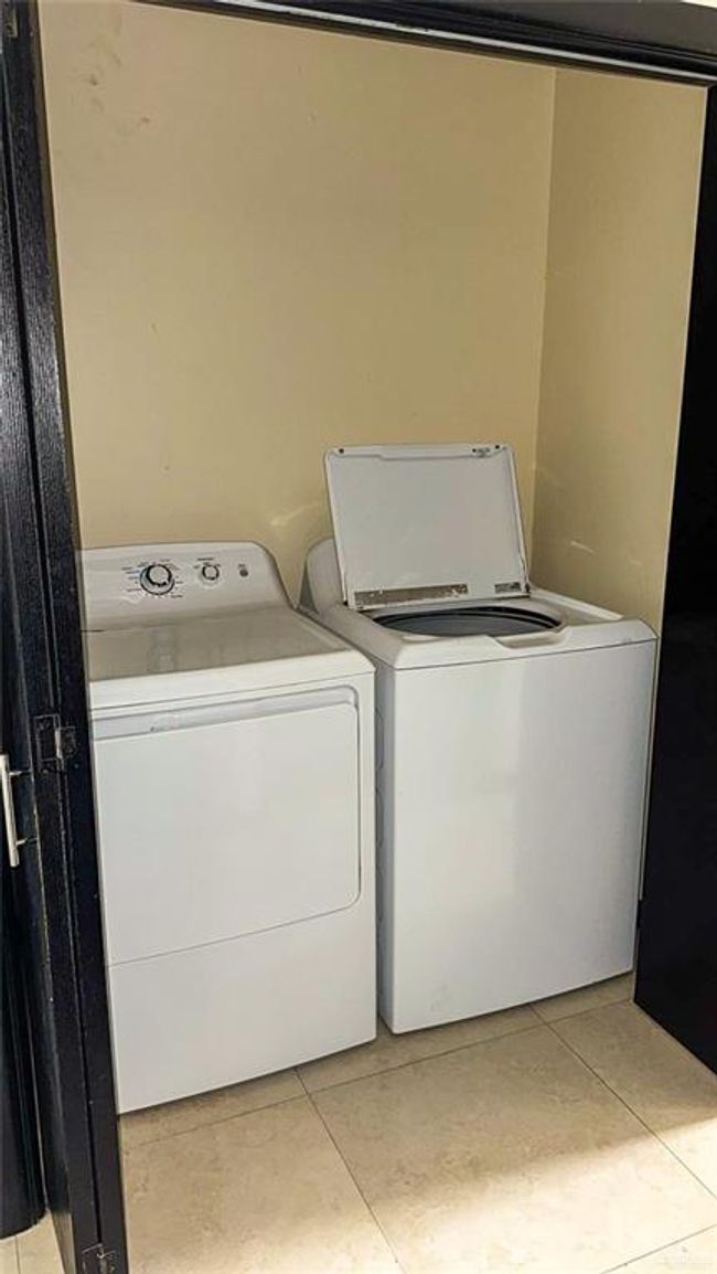Laundry area with washing machine and clothes dryer and light tile patterned flooring | Image 15