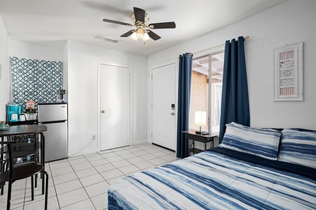 Bedroom featuring freestanding refrigerator, light tile patterned flooring, and a ceiling fan | Image 4