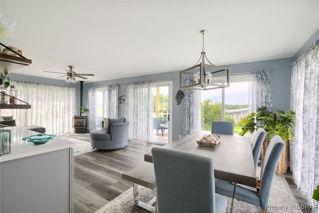 Dining room featuring ceiling fan with notable chandelier, light hardwood / wood-style floors, a wood stove, and a wealth of natural light | Image 31