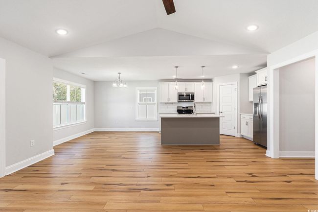 Kitchen with appliances with stainless steel finishes, lofted ceiling, light wood finished floors, white cabinets, and backsplash | Image 8