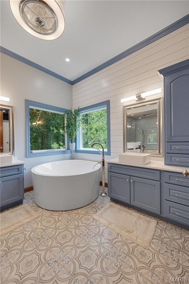 Bathroom featuring vanity, a freestanding tub, crown molding, and tile patterned flooring | Image 24