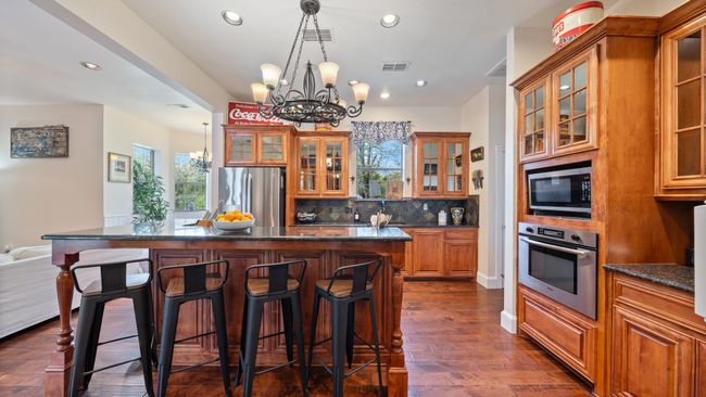 Kitchen with visible vents, a breakfast bar, appliances with stainless steel finishes, brown cabinetry, and a notable chandelier | Image 10