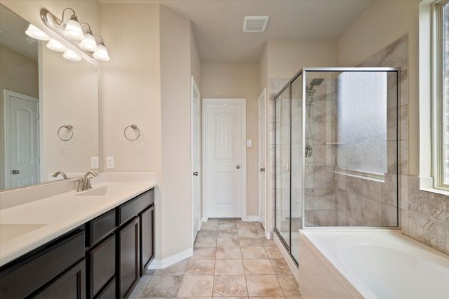Bathroom featuring a shower stall, double vanity, a garden tub, and baseboards | Image 17