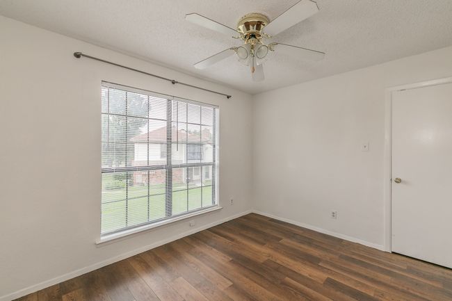 Empty room with a ceiling fan, dark wood-style floors, baseboards, and a textured ceiling | Image 19