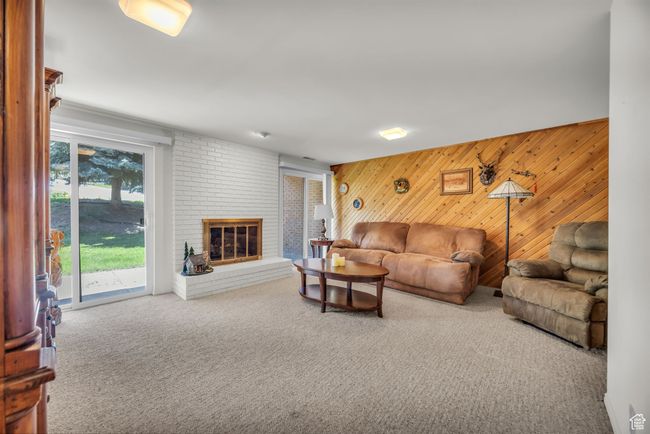 Carpeted living room with wooden walls and a fireplace | Image 20