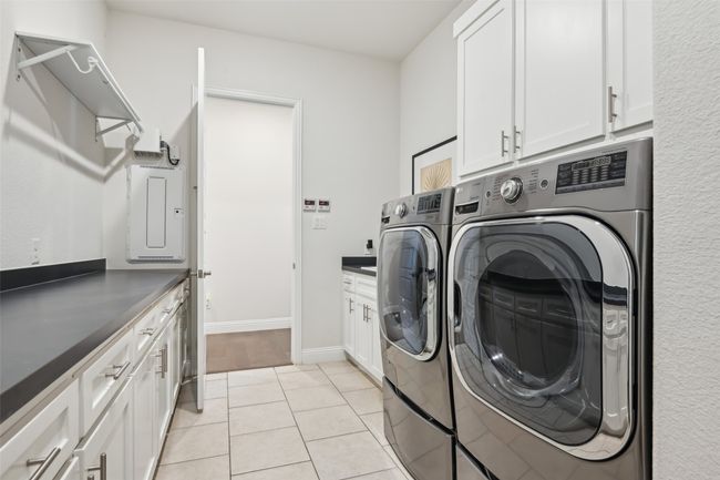 Laundry area featuring independent washer and dryer, cabinet space, and light tile patterned flooring | Image 25