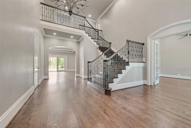 Entryway featuring arched walkways, a towering ceiling, wood finished floors, stairs, and crown molding | Image 6