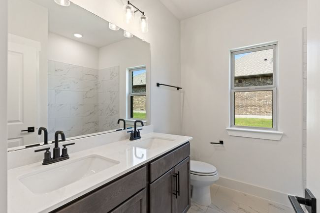 Bathroom with marble look tile flooring, double vanity, and a shower | Image 18