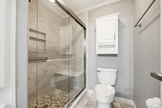 Bathroom featuring toilet, a stall shower, crown molding, and baseboards | Image 23