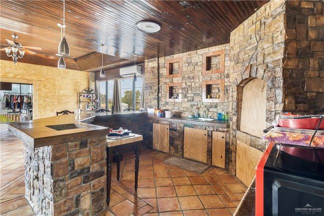 Kitchen with wood ceiling, an AC wall unit, ceiling fan, butcher block counters, and a sink | Image 11