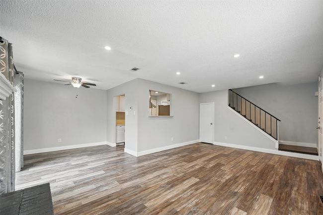 Unfurnished living room with ceiling fan, wood finished floors, stairs, recessed lighting, and a textured ceiling | Image 5