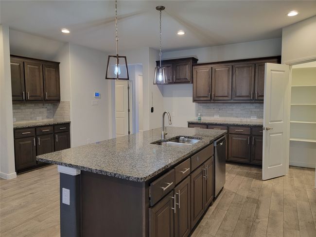 Kitchen featuring a sink, dishwasher, light wood-style floors, dark brown cabinets, and recessed lighting | Image 8