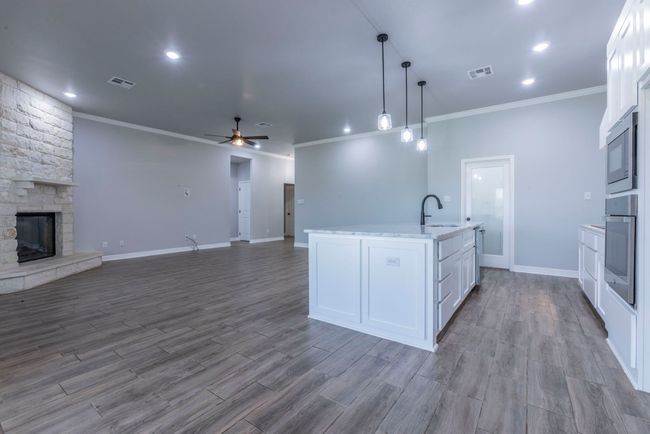 Kitchen featuring crown molding, ceiling fan, open floor plan, oven, and white cabinets | Image 10