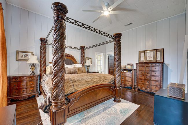Bedroom with wood walls, hardwood / wood-style flooring, visible vents, and ceiling fan | Image 21