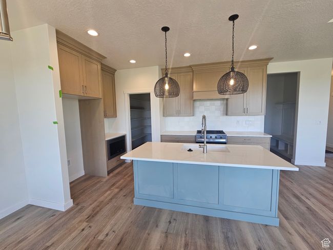 Kitchen with baseboards, light countertops, tasteful backsplash, wood finished floors, and a textured ceiling | Image 8