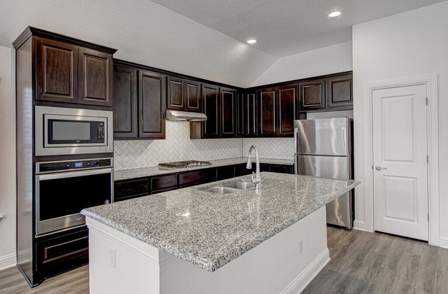 Kitchen featuring stainless steel appliances, a sink, light wood finished floors, tasteful backsplash, and lofted ceiling | Image 9