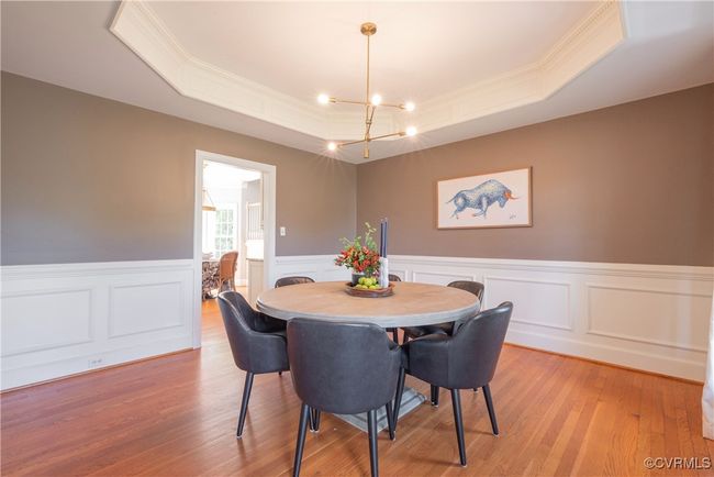 Dining area featuring a tray ceiling, light wood-type flooring, ornamental molding, wainscoting, and a notable chandelier | Image 13