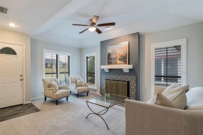 Living room with a tray ceiling, carpet, ceiling fan, and a tile fireplace | Image 3