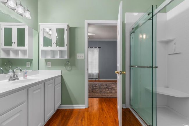 Full bath with vanity, wood finished floors, baseboards, an enclosed shower, and ornamental molding | Image 27